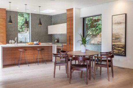Modern open-concept kitchen and dining area with wood tones, geometric patterns, and large windows.
