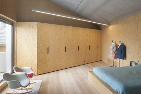 Spacious bedroom with OSB wood paneling, built-in closets, and minimalist furnishings.