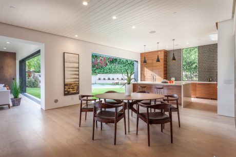 Modern, open-plan kitchen and dining space with natural wood accents, large windows, and contemporary decor.