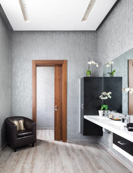 Minimalist bathroom design with wood door, textured walls, and sleek black cabinetry.