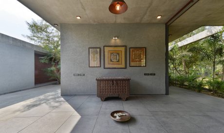 A modern, minimalist interior with a woven storage trunk and framed artwork on the walls.
