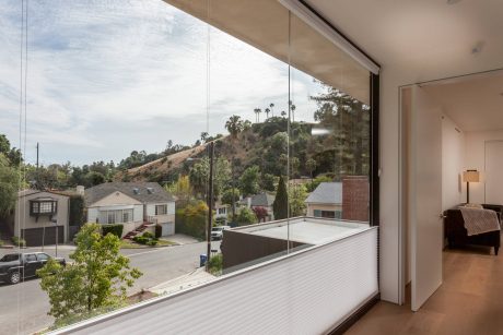Spacious room with floor-to-ceiling windows offering panoramic views of the hilly neighborhood.