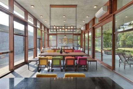 A spacious, modern dining room with a wooden frame, colorful chairs, and large windows.