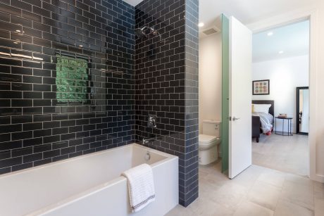 Sleek black tile walls, minimalist white fixtures, and an open bathroom layout.