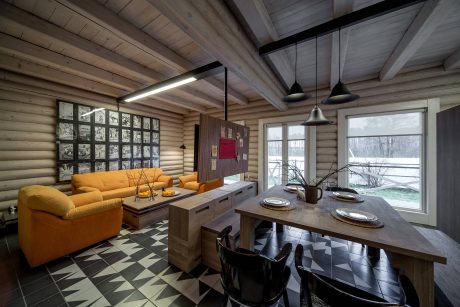 Rustic log cabin interior with modern furnishings, geometric tiled floor, and large windows.