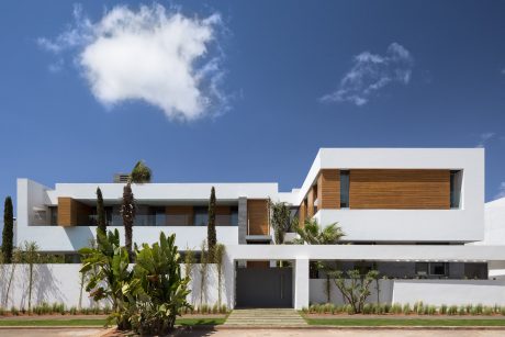 A sleek, modern residential building with clean lines, wood accents, and lush landscaping.