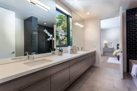 Spacious bathroom with modern vanity, dark tile wall, and large window providing natural light.