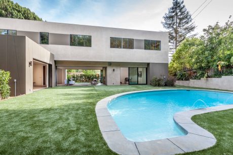 Modern two-story home with large windows, grassy yard, and inviting swimming pool.