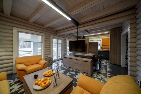 A cozy log cabin interior featuring wooden beams, patterned flooring, and modern furnishings.