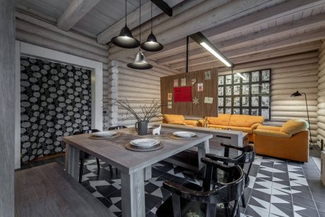 Contemporary rustic interior with exposed wood beams, patterned tile floor, and colorful furniture.