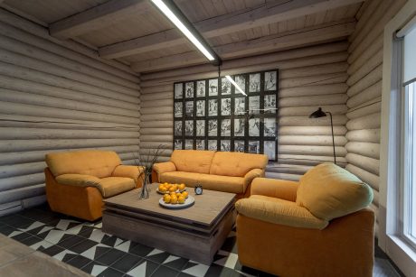 Cozy log cabin interior with yellow upholstery, wood-paneled walls, and geometric patterned floor.