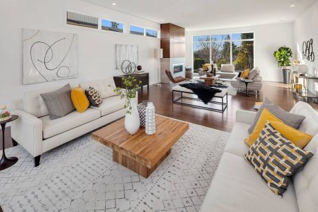 Spacious, open-concept living room with modern furnishings, large windows, and abstract artwork.