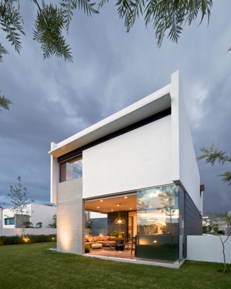 A modern, minimalist home with clean lines, large glass windows, and a cozy outdoor living area.
