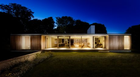 Contemporary open-plan home with floor-to-ceiling windows, wooden exterior, and serene landscape.