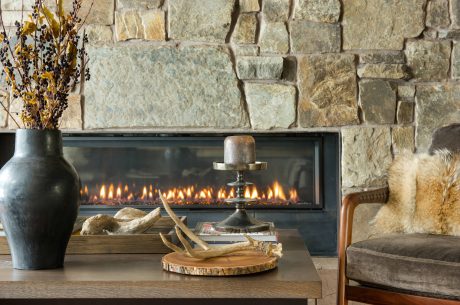 Cozy living room with rustic stone wall, fireplace, and decorative accents.