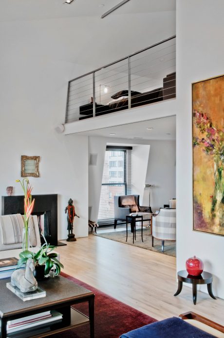 Stylish modern living space with high ceiling, metal railing, and diverse decor elements.