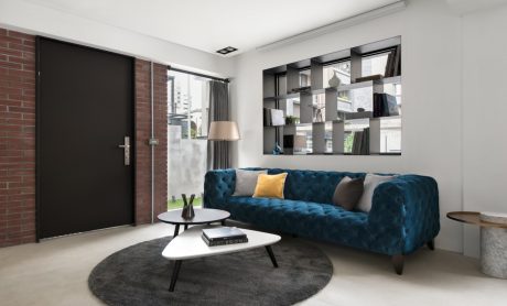 Contemporary living room with tufted blue sofa, modern coffee tables, and a geometric wall shelf.