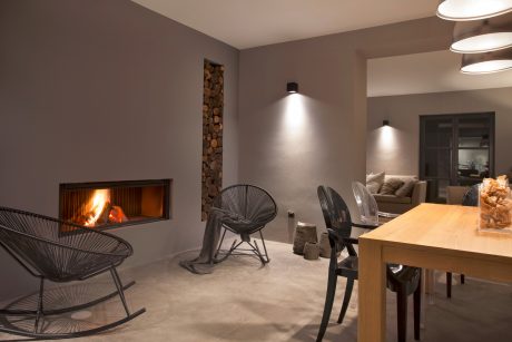 Modern living room with cozy fireplace, wood accent wall, and minimalist furniture.
