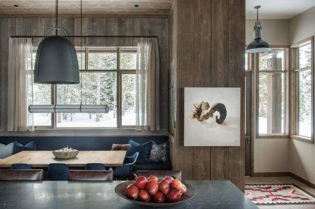 Rustic wood paneling, modern pendant lights, and a cozy dining nook with plush seating.