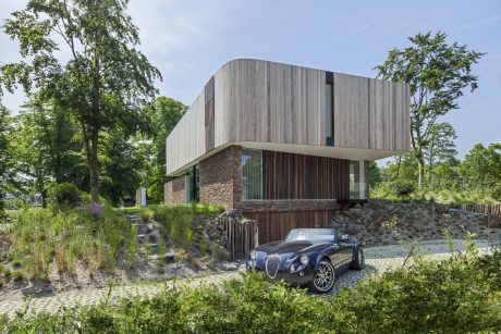 A modern, wooden-clad structure with a distinctive cantilevered design, nestled among lush greenery.