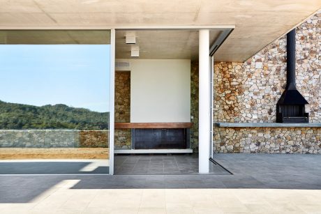 Modern minimalist interior with large glass windows, stone accent wall, and fireplace.
