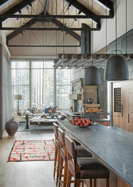 A spacious, rustic kitchen with wooden beams, large windows, and a stone fireplace.