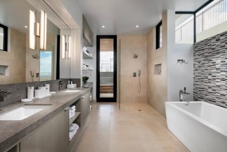 Elegant modern bathroom with large vanity, sleek tiled walls, and floor-to-ceiling window.