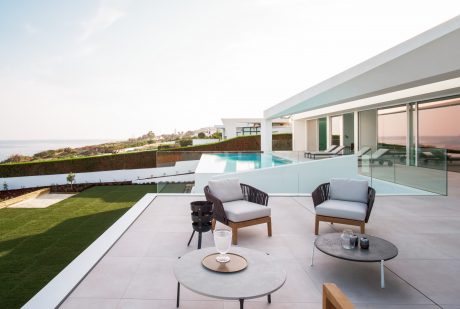 Modern beachfront home with sleek, geometric architecture, infinity pool, and elegant outdoor seating.
