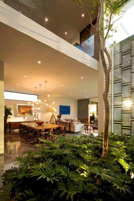 This striking indoor garden features lush greenery, high ceilings, and a warm, minimalist decor.