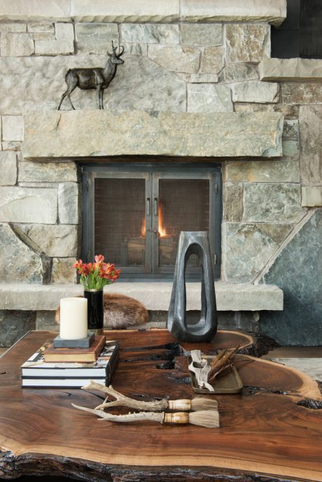 A cozy stone fireplace with rustic decor, including antlers, books, and candles, creating a warm, inviting ambiance.