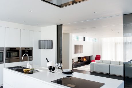 Sleek, modern kitchen with integrated appliances, open-concept living room, and gas fireplace.