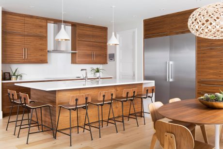 Modern kitchen with wooden cabinets, island, and pendant lighting fixtures.