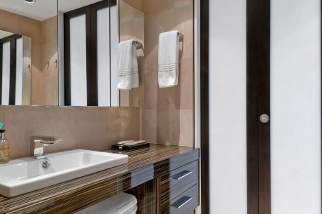 Contemporary bathroom with wood-paneled vanity, floating sink, and framed mirrors.