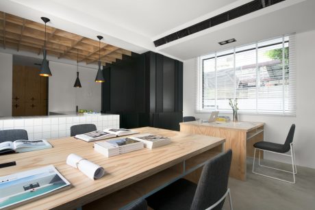 Sleek, modern workspace with wooden accents, black cabinetry, and large window overlooking greenery.