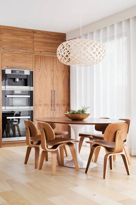 Modern kitchen with wooden cabinetry, a round dining table, and sculptural lighting fixture.