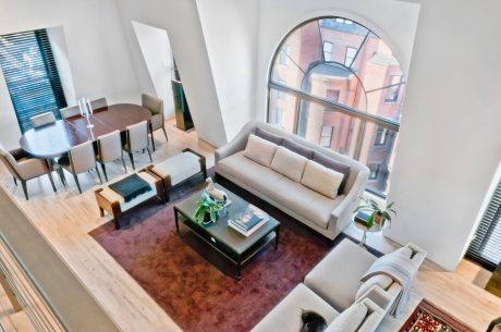 Airy living room with arched window, modern furnishings, and earthy color palette.