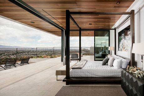 Expansive glass-walled bedroom with wooden ceiling and panoramic city views.