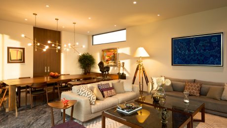 Warm, modern living space with wooden furniture, pendant lighting, and colorful artwork.