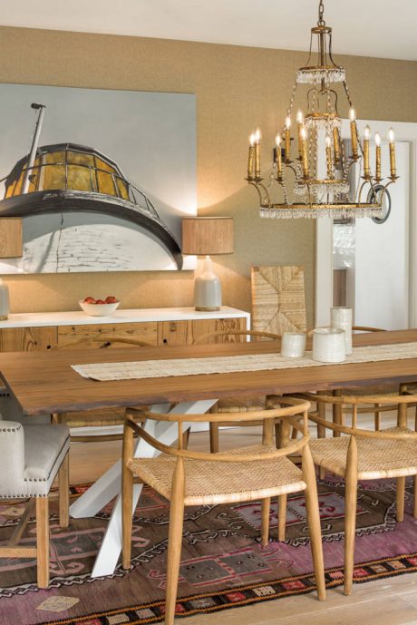 Warm, rustic dining area with wood furnishings, ornate chandelier, and patterned rug.