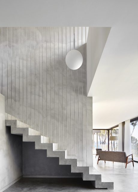Clean, modern interior with concrete stairs, white walls, and a minimalist pendant light.