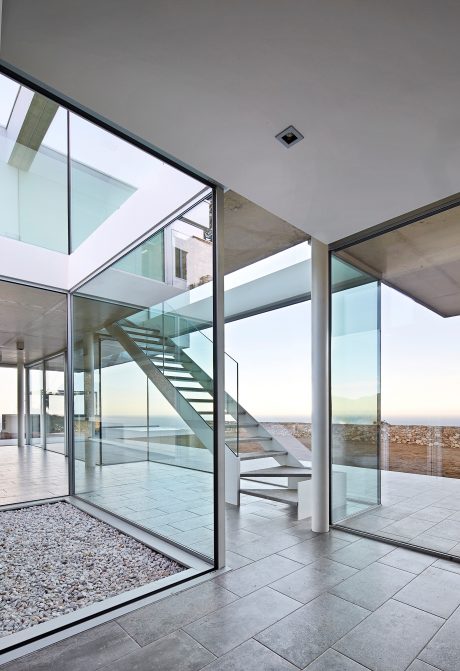 Sleek, modern architecture with glass walls, steel staircase, and a view of the outdoors.
