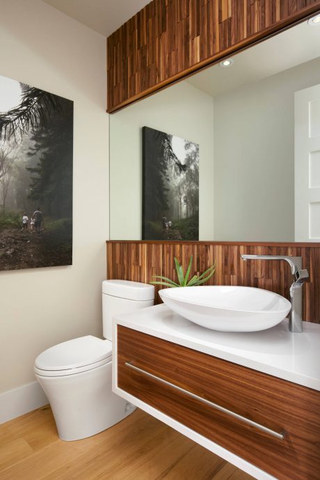Cozy bathroom with wooden panels, vessel sink, and nature-inspired artwork.