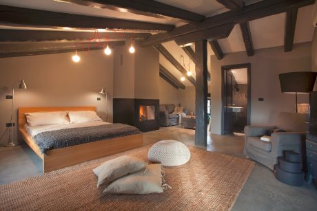 Rustic bedroom with exposed wooden beams, plush textiles, and cozy seating area.