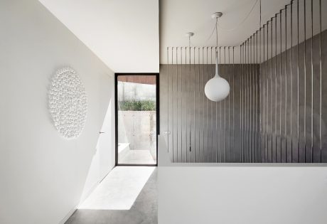A modern, minimalist interior with a geometrical wall panel and a large window framing the outdoors.