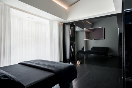 Dark modern bedroom with sleek, minimalist design elements and built-in closet.