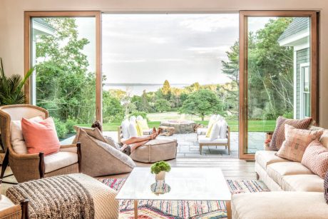 Spacious open-concept living area with floor-to-ceiling windows showcasing serene lakefront view.