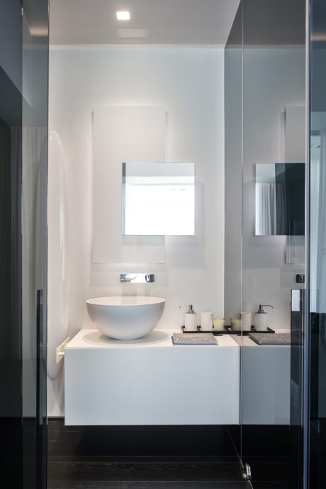 Minimalist bathroom design with a freestanding ceramic basin, recessed lighting, and mirrored walls.