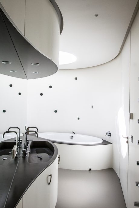A modern, minimalist bathroom design with curved ceiling, white and gray palette.