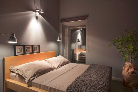 An intimate bedroom with warm lighting, wooden headboard, and textured gray rug.