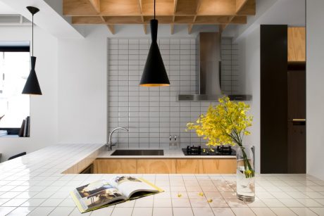 Sleek, modern kitchen with tiled backsplash, wood cabinetry, and black pendant lamps.